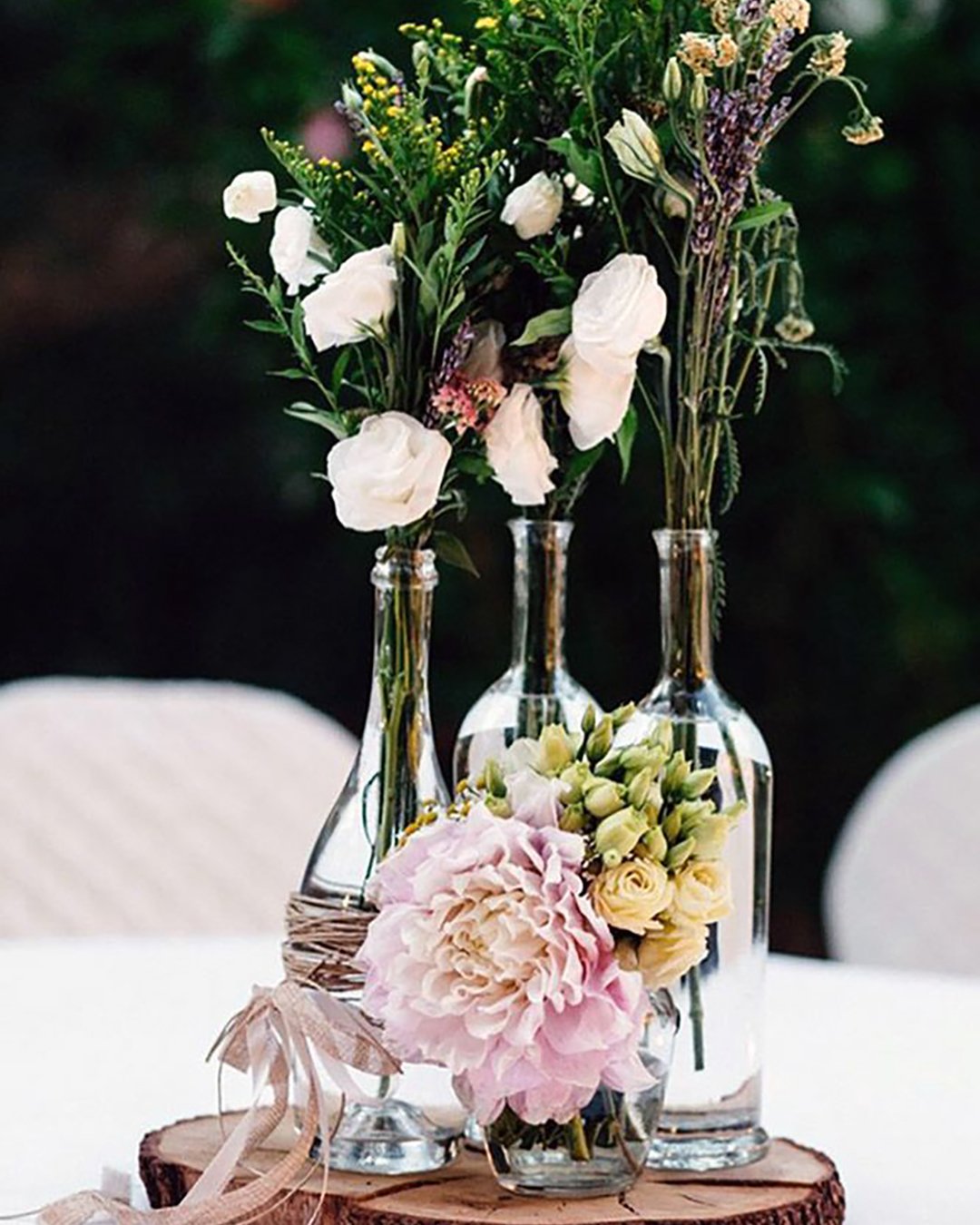 wedding table decorations on a wooden bag in glass bottles flowers rebecca silenzi via instagram
