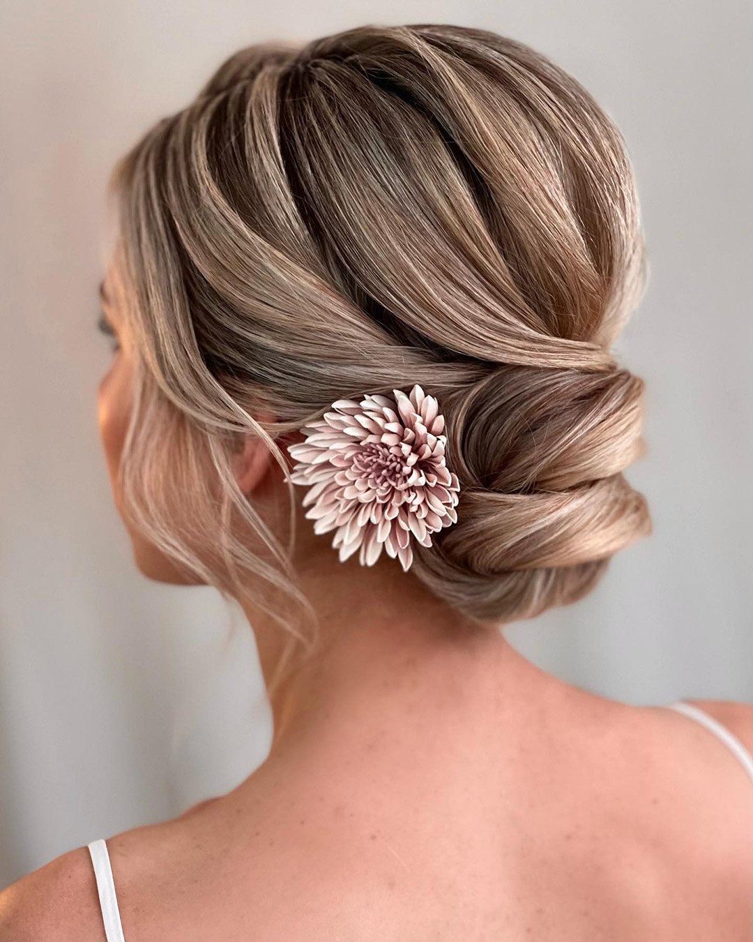 spring wedding hairstyles low bun with single flower kasia_fortuna